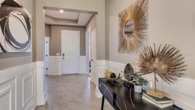 foyer with a raised ceiling and light tile patterned floors