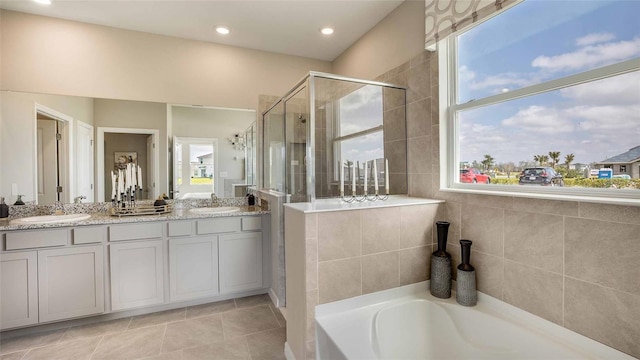 bathroom with tile patterned floors, independent shower and bath, vanity, and a healthy amount of sunlight