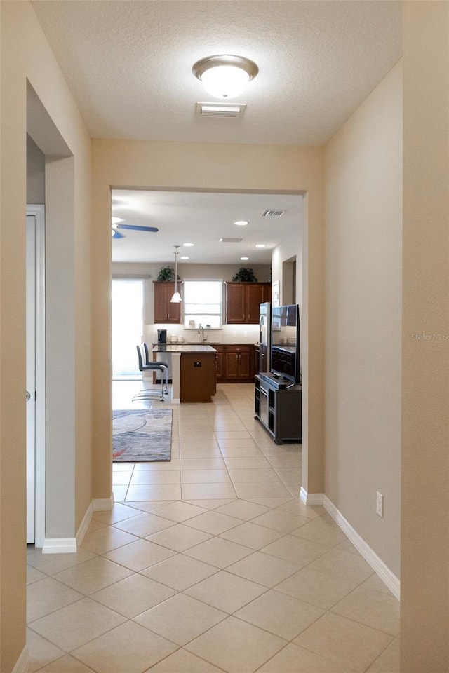 hallway featuring light tile patterned flooring and a textured ceiling