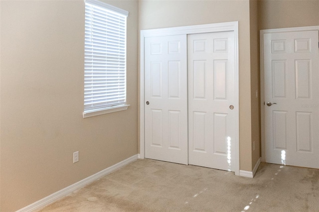 unfurnished bedroom featuring a closet and light colored carpet