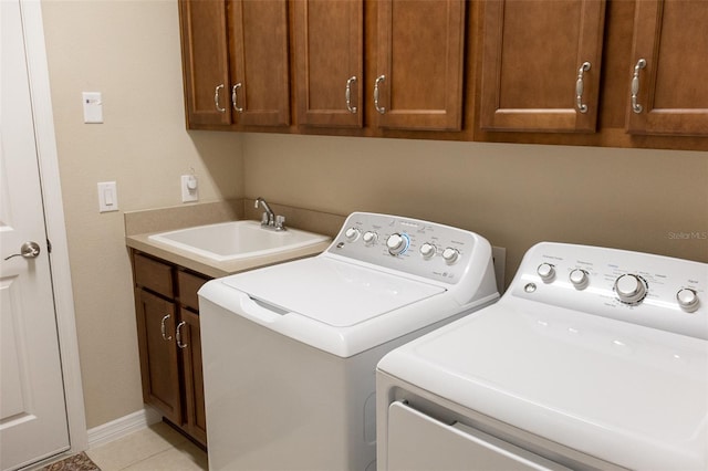 clothes washing area featuring light tile patterned flooring, cabinets, sink, and washing machine and dryer