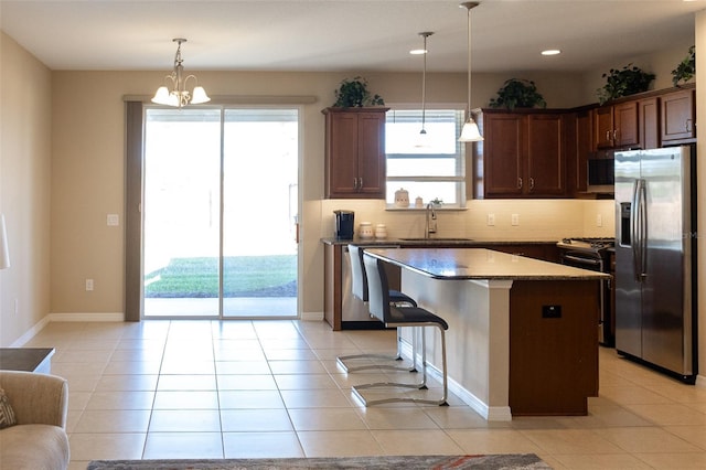 kitchen with a center island, sink, tasteful backsplash, decorative light fixtures, and stainless steel appliances