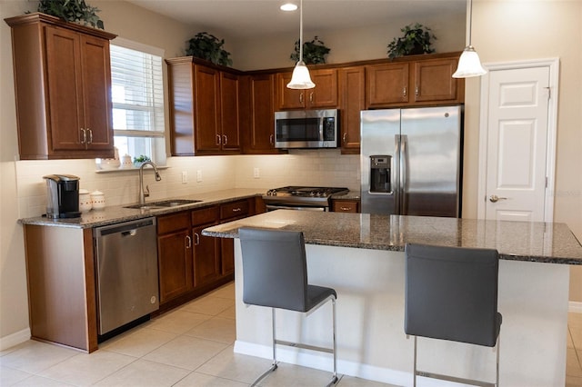 kitchen featuring a center island, sink, hanging light fixtures, a kitchen bar, and stainless steel appliances