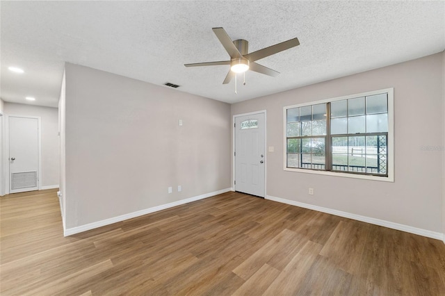 empty room featuring ceiling fan, light hardwood / wood-style floors, and a textured ceiling