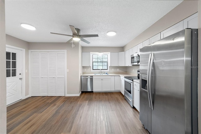 kitchen with dark hardwood / wood-style flooring, white cabinetry, sink, and appliances with stainless steel finishes