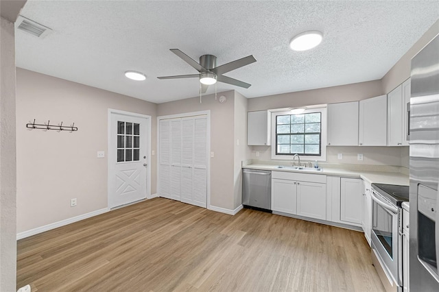 kitchen featuring a textured ceiling, stainless steel appliances, white cabinetry, and light hardwood / wood-style flooring