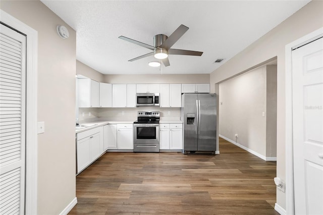 kitchen featuring dark hardwood / wood-style flooring, a textured ceiling, stainless steel appliances, ceiling fan, and white cabinetry