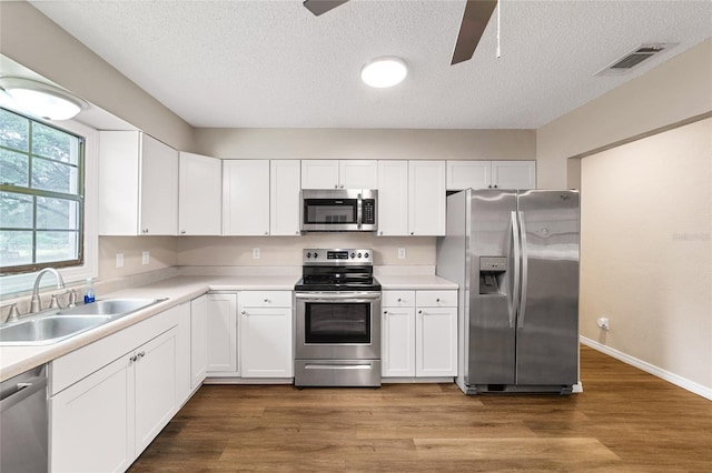 kitchen with hardwood / wood-style flooring, white cabinetry, sink, and appliances with stainless steel finishes