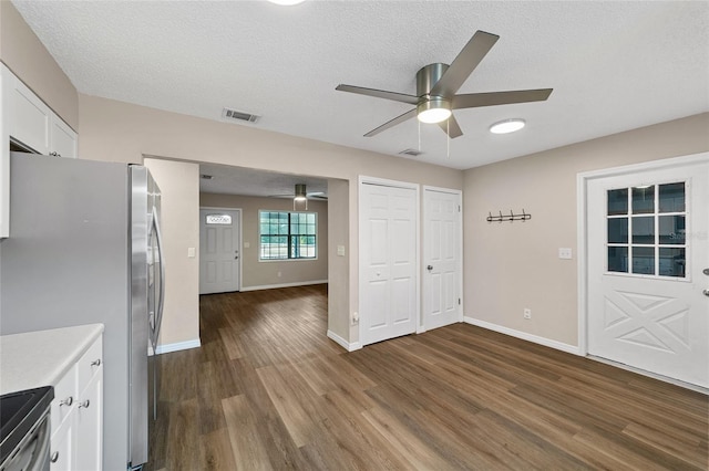 interior space with white cabinets, dark hardwood / wood-style floors, a textured ceiling, and appliances with stainless steel finishes