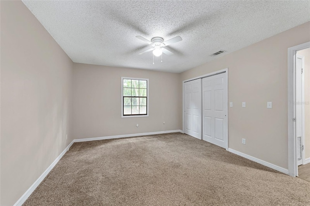 unfurnished bedroom with carpet flooring, ceiling fan, a closet, and a textured ceiling