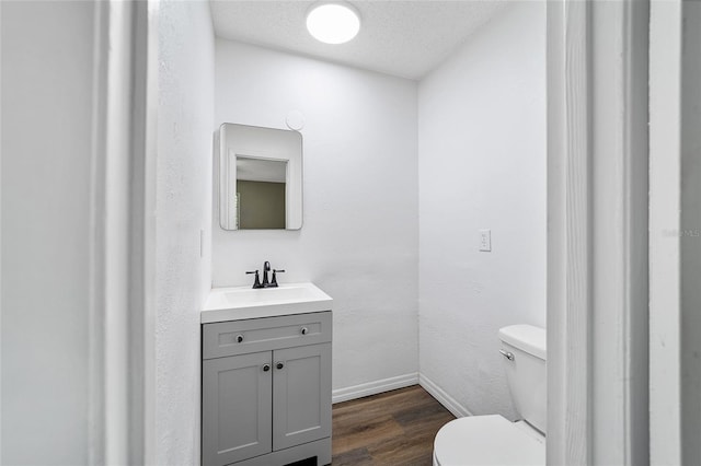 bathroom with hardwood / wood-style floors, vanity, a textured ceiling, and toilet