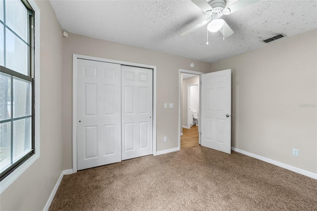 unfurnished bedroom featuring carpet, ceiling fan, a textured ceiling, and a closet