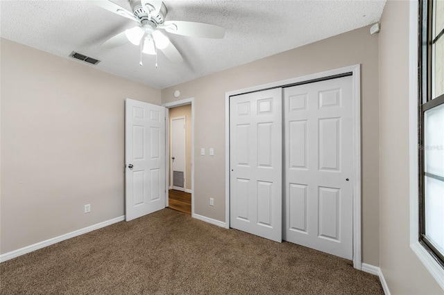 unfurnished bedroom featuring ceiling fan, a closet, carpet floors, and a textured ceiling