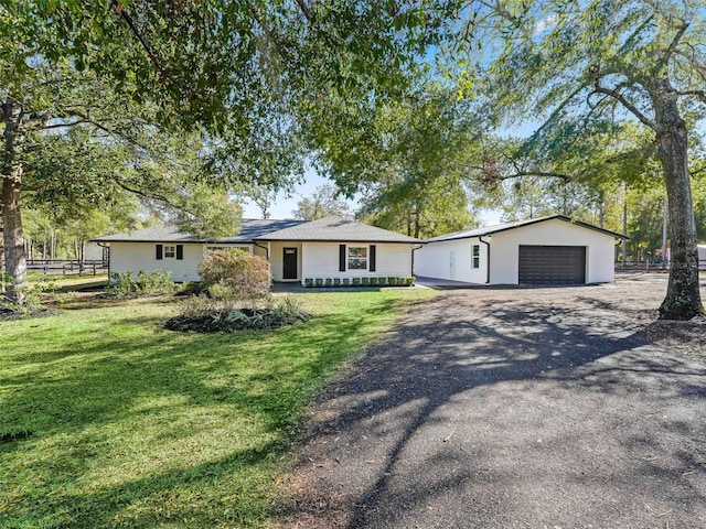 ranch-style house with an outbuilding, a front yard, fence, and gravel driveway