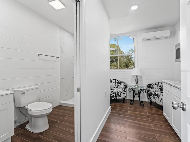 full bath with walk in shower, wood finish floors, toilet, vanity, and a wall mounted AC