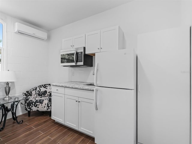 kitchen with a wall mounted AC, stainless steel microwave, white cabinetry, freestanding refrigerator, and wood tiled floor