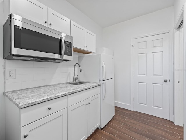 kitchen with stainless steel microwave, backsplash, wood finish floors, white cabinets, and a sink