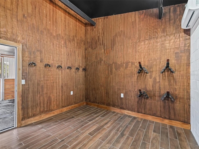 empty room featuring wood walls, wood tiled floor, and a wall unit AC