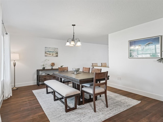 dining space with a chandelier, a textured ceiling, baseboards, and dark wood-style flooring