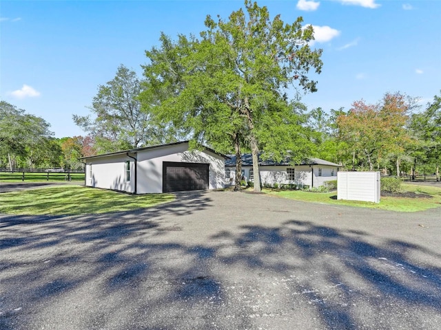 view of front of home with stucco siding, a front lawn, a garage, and fence