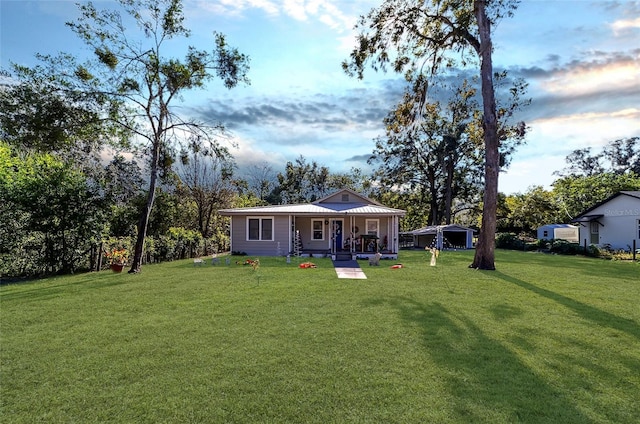 rear view of house with covered porch and a yard