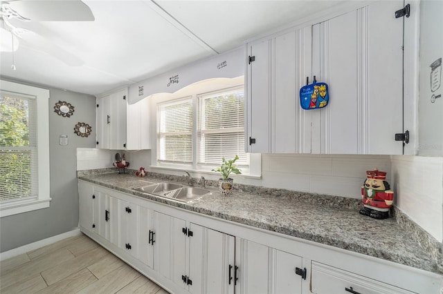 kitchen with backsplash, white cabinetry, sink, and ceiling fan