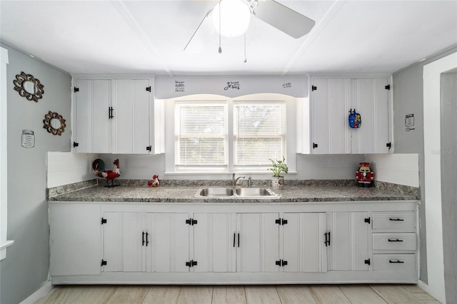 kitchen with ceiling fan, light wood-type flooring, white cabinetry, and sink