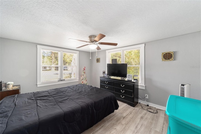 bedroom featuring ceiling fan, a textured ceiling, and light wood-type flooring