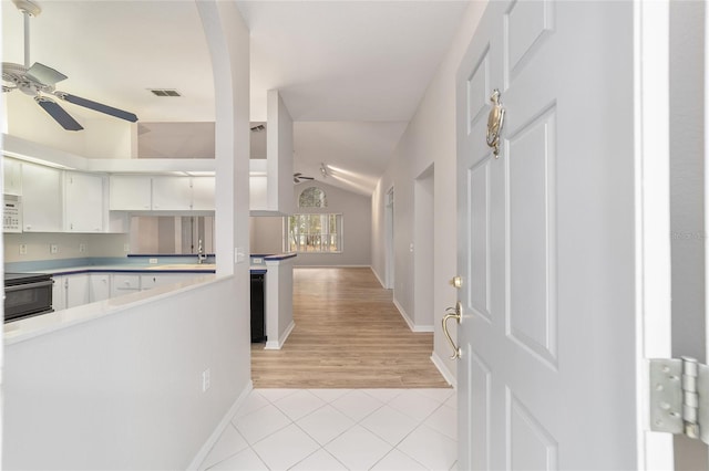 interior space featuring lofted ceiling, black range with electric stovetop, ceiling fan, light hardwood / wood-style floors, and white cabinetry