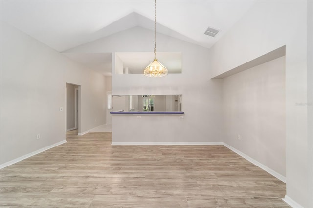 unfurnished living room with high vaulted ceiling, a notable chandelier, and light wood-type flooring