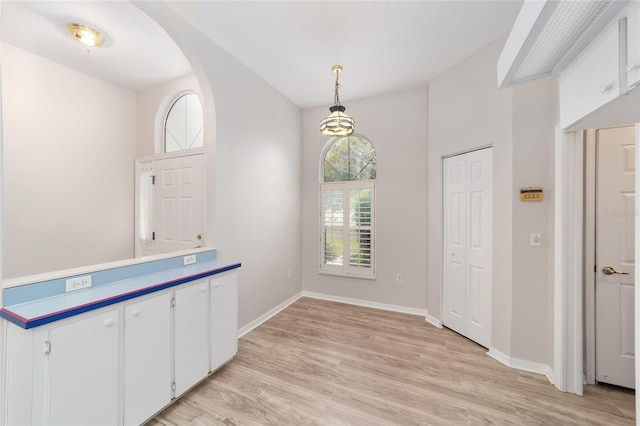 interior space featuring decorative light fixtures, white cabinetry, and light hardwood / wood-style flooring