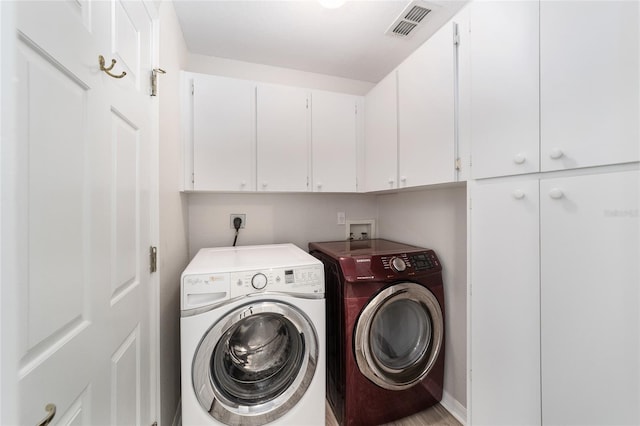 laundry room with washer and dryer and cabinets