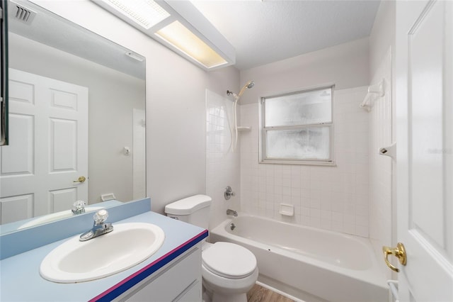 full bathroom with vanity, tiled shower / bath combo, toilet, a textured ceiling, and wood-type flooring