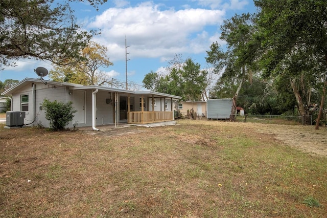 rear view of property featuring central air condition unit and a lawn