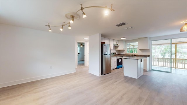 kitchen with white cabinetry, stainless steel fridge, stove, a kitchen island, and light wood-type flooring