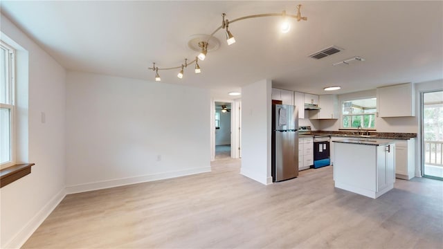 kitchen with white cabinets, stainless steel fridge, light hardwood / wood-style floors, a kitchen island, and range