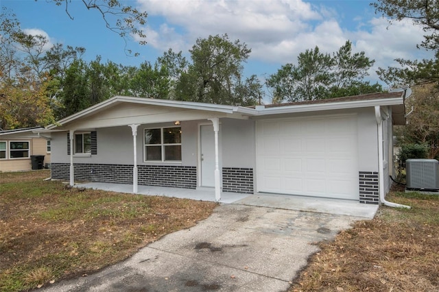 ranch-style house featuring a porch, central AC unit, and a garage