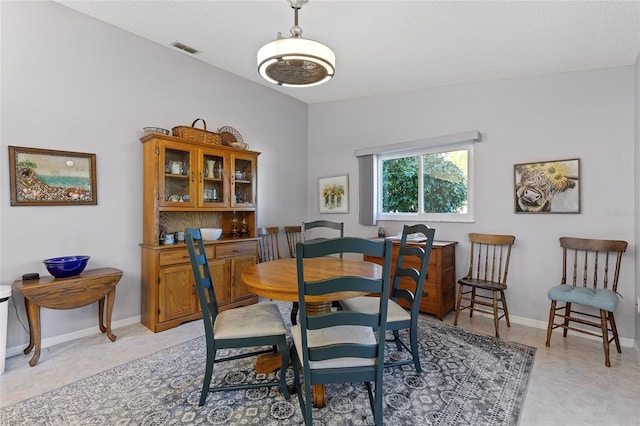 tiled dining area featuring a textured ceiling and lofted ceiling