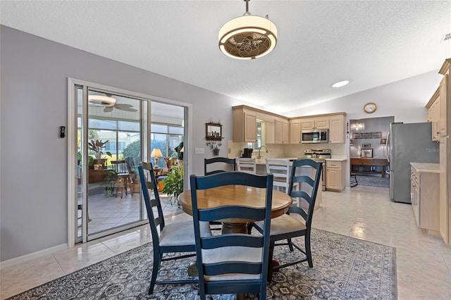 tiled dining room with ceiling fan, sink, a textured ceiling, and vaulted ceiling