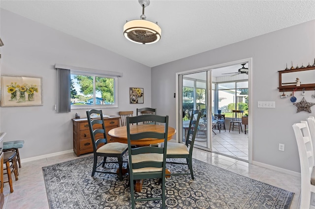 tiled dining space featuring a textured ceiling, vaulted ceiling, and ceiling fan