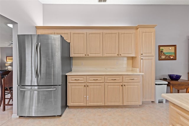 kitchen featuring stainless steel refrigerator, light brown cabinetry, and light tile patterned floors