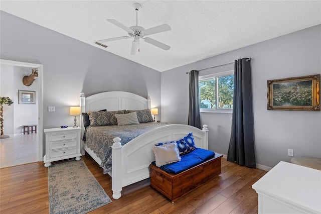 bedroom featuring ceiling fan, dark hardwood / wood-style flooring, and a textured ceiling