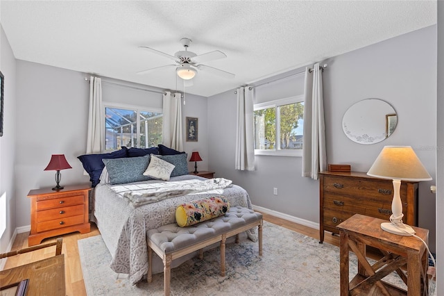 bedroom featuring ceiling fan, light hardwood / wood-style floors, and a textured ceiling