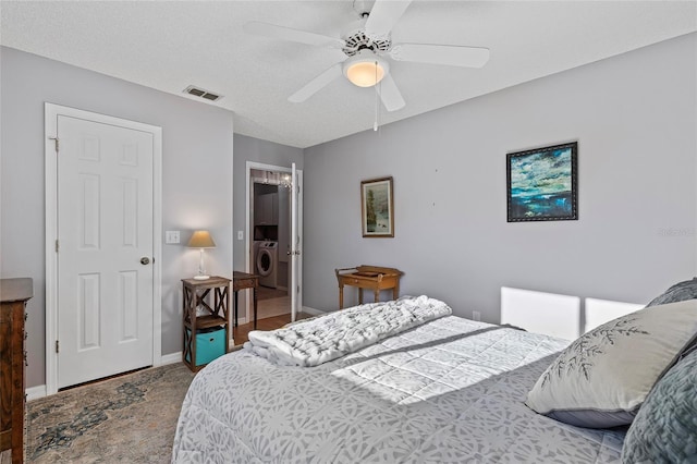 bedroom with ceiling fan, a textured ceiling, and washer / dryer