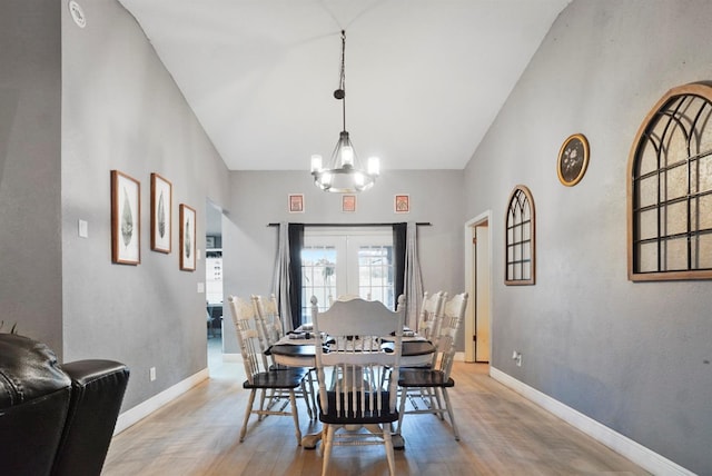 dining room featuring light hardwood / wood-style floors, vaulted ceiling, and an inviting chandelier