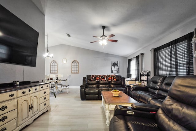 living room with ceiling fan with notable chandelier, lofted ceiling, and light hardwood / wood-style flooring