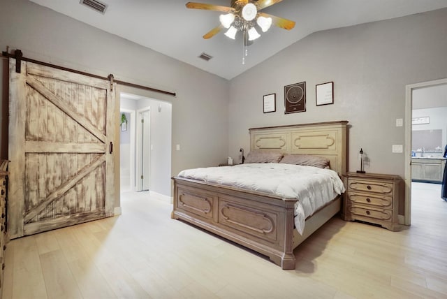 bedroom with ceiling fan, a barn door, light wood-type flooring, and lofted ceiling