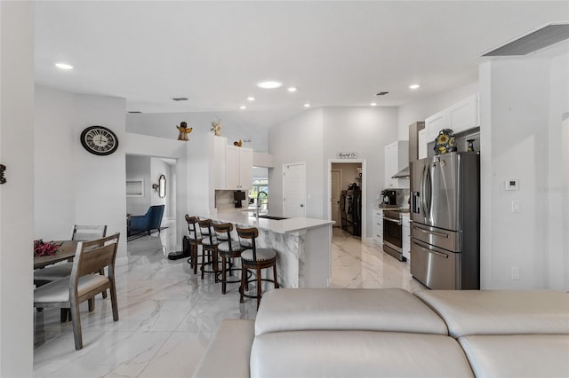 kitchen featuring kitchen peninsula, appliances with stainless steel finishes, sink, white cabinetry, and a breakfast bar area