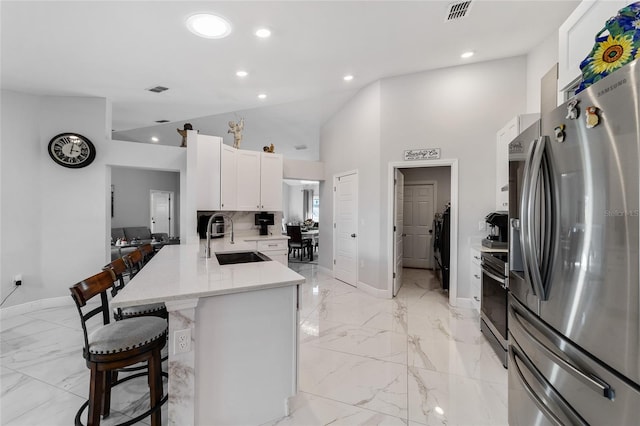 kitchen with kitchen peninsula, appliances with stainless steel finishes, a breakfast bar, sink, and white cabinets