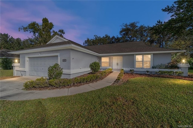 ranch-style home featuring a garage and a yard